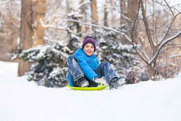 Fototapeta na wymiar boy sitting on sledges and sliding down.