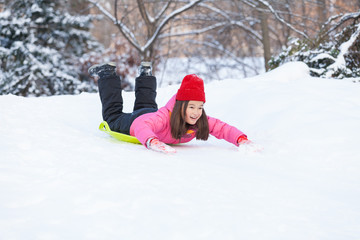 Fototapeta na wymiar girl sliding on snow from hill fast.
