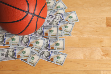 Obraz premium Basketball on pile of one hundred dollar bills