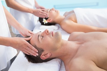 Obraz na płótnie Canvas Content couple enjoying head massages poolside