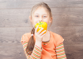 little girl holding vegetables on a wooden background