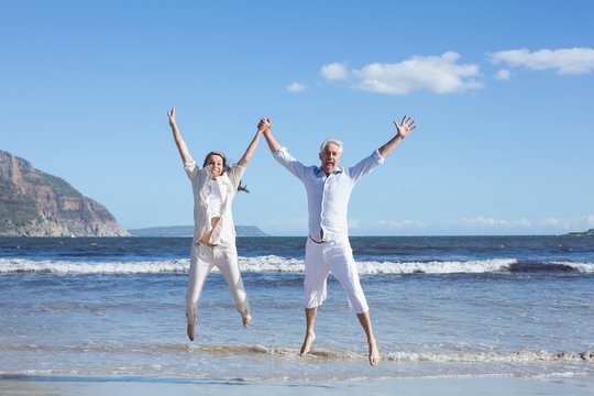 Happy couple jumping up barefoot on the beach