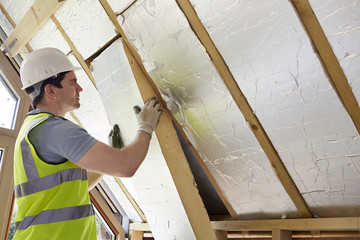 Builder Fitting Insulation Into Roof Of New Home - obrazy, fototapety, plakaty