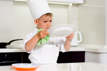 Cute young chef checking his dinner plates