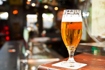 	Glass of light beer on a dark pub