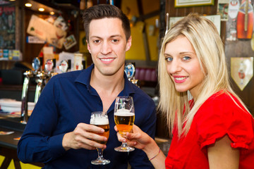 Beautiful couple enjoying beer in a pub 
