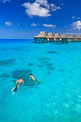 Couple snorkeling in the blue lagoon, Bora Bora, South Pacific  - obrazy, fototapety, plakaty