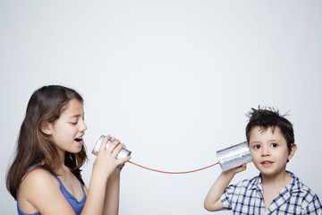Kids using a can as telephone against gray background