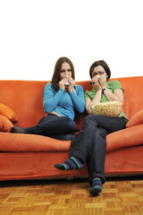 female friends eating popcorn and watching tv at home