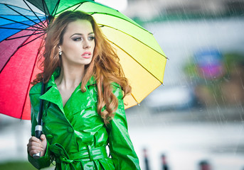 Beautiful woman in bright green coat posing in the rain