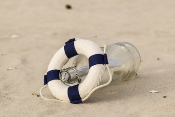 Fototapeta na wymiar Rettungsring und Flasche am Strand