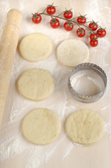 mini pizza dough on a floury wooden board