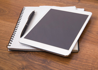 Blank modern digital tablet with papers and pen on a wooden desk