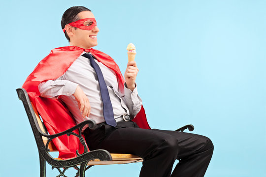 Superhero holding an ice cream seated on bench