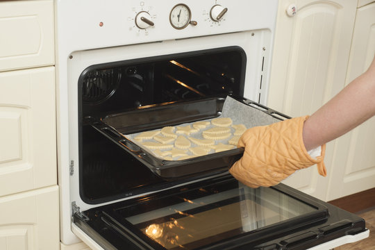 Woman put cookies in stove