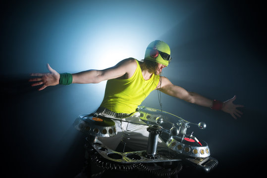 dj man with headphones playing on vinyl in a nightclub.