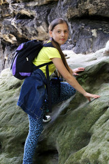 girl climbs on a rock outdoors