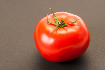 One single perfect red tomato on dark table or background.