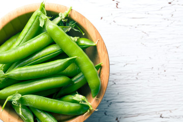 green pea pods in wooden bowl