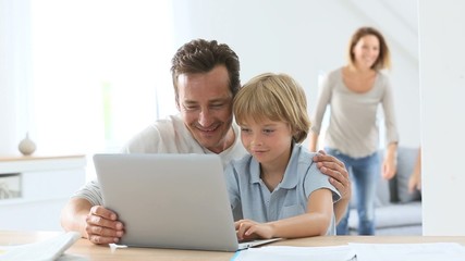 Parents with children using laptop computer at home - Powered by Adobe