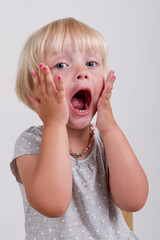 Portrait of surprised blond little girl, Isolated on grey