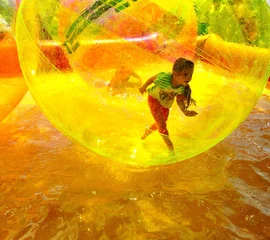 Zelfklevend Fotobehang child playing in the pool inside a plastic ball © schab