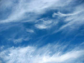 Blue sky background with wavy fleecy clouds