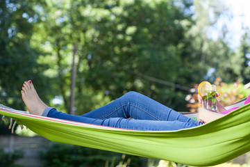 Woman resting with drink on hammock