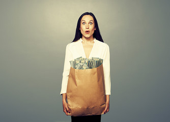 amazed woman holding paper bag with money