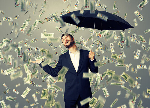 man standing under money rain