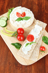 Tasty crispbreads with vegetables on wooden background