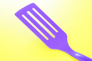 Plastic kitchen utensil on yellow background