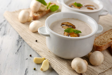 Mushroom soup in white pots, on napkin,  on wooden background