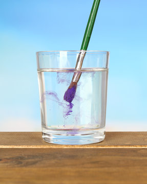 Brush with color paint in glass of water,