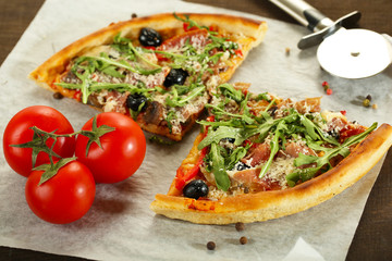 Pizza with arugula on cutting board, on color wooden background