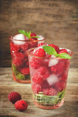 Summer juice with fresh raspberries mint and ice in a glass