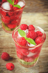 Summer juice with fresh raspberries mint and ice in a glass