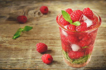 Summer juice with fresh raspberries mint and ice in a glass