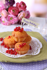Tasty muffins on plate, on wooden table, on bright background