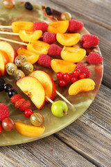 Fresh fruit skewers for healthy snack on wooden table close up
