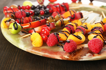 Fresh fruit skewers for healthy snack on wooden table close up