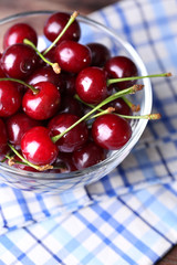 Cherries in color bowl on wooden background