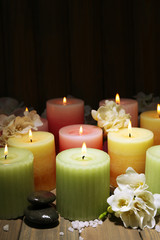 Beautiful candles with flowers on wooden background