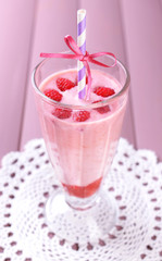 Glass of raspberry smoothie drink on wooden background