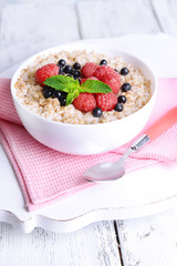 Tasty oatmeal with berries on table close-up