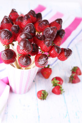Strawberry in chocolate on skewers in cup on table close-up