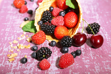 Fototapeta na wymiar Different ripe berries in sugar cone, on purple background