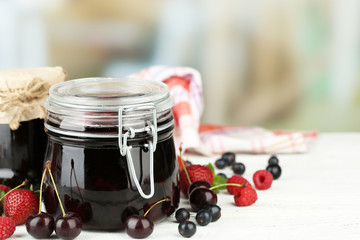 Tasty jam with berries in glass jars on wooden table