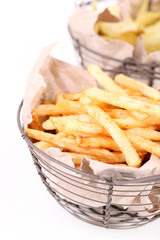 Tasty french fries in metal basket and potato chips, isolated