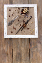 Wooden frame, vintage spoon and spices on wooden background